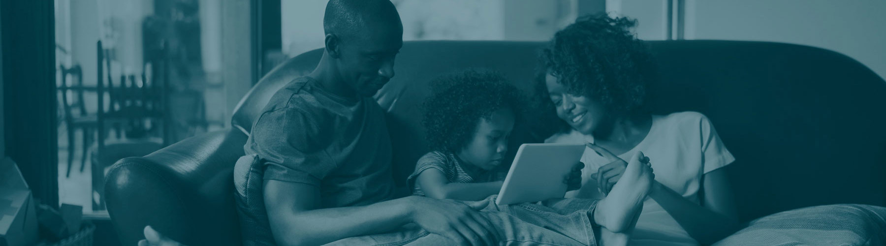 A family sitting on a couch looking at a tablet